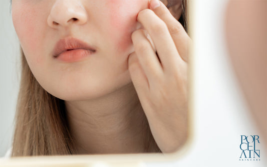 A woman concerned about red cheeks while looking at her reflection in the mirror
